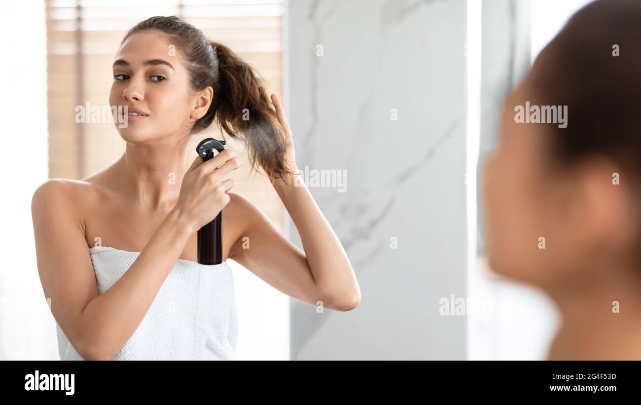 Lady Styling capelli spruzzando Hairspray sulle estremità divise in bagno Foto Stock
