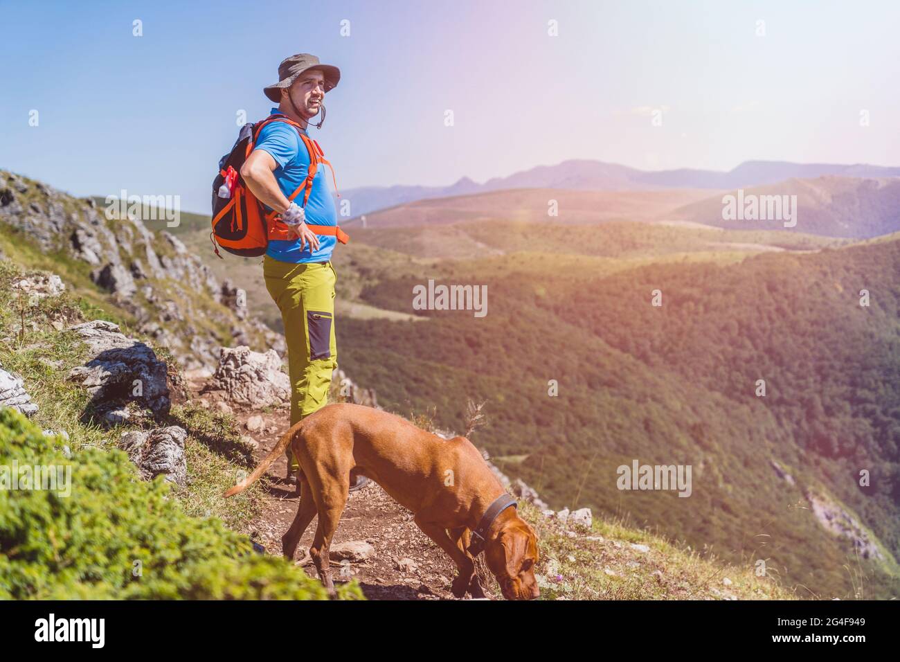 Giovane uomo Hiker viaggiatore con zaino con il suo cane guardando il paesaggio Foto Stock