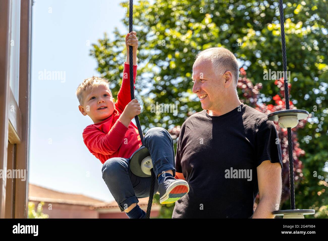 Padre che gioca con il suo figlio di 3 anni sul parco giochi Foto Stock