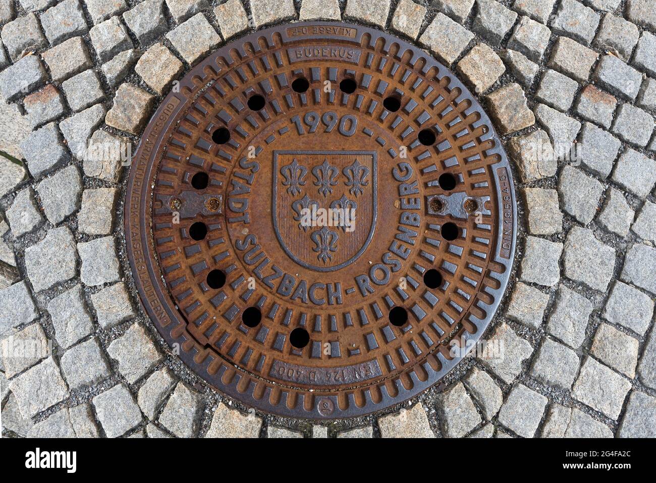 Copertura di tombino arrugginito con stemma della città, Sulzbach-Rosenberg, Palatinato superiore, Baviera, Germania Foto Stock