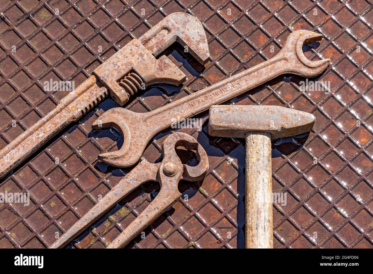 Vecchio utensile con inglese, chiave, pinza di fissaggio, martello su piastra in ferro arrugginito umido, Germania Foto Stock