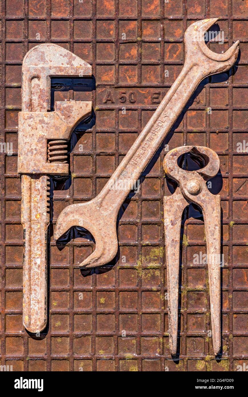 Vecchia chiave, chiave a forchetta rotante o inglese con pinze a pinza o a punta, utensile arrugginito su piastra in ferro arrugginito umido, Germania Foto Stock