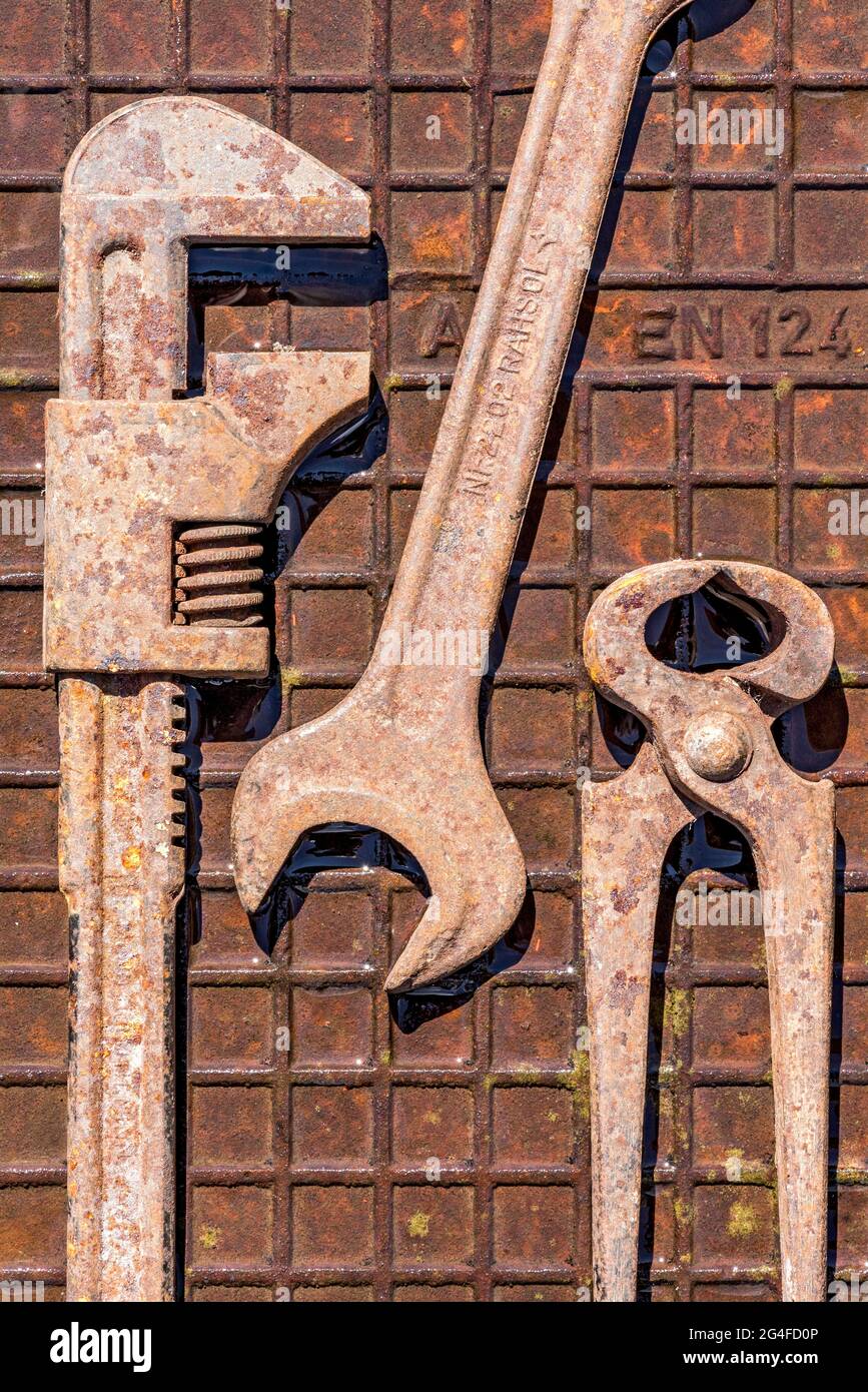Vecchia chiave, chiave a forchetta rotante o inglese con pinze a pinza o a punta, utensile arrugginito su piastra in ferro arrugginito umido, Germania Foto Stock