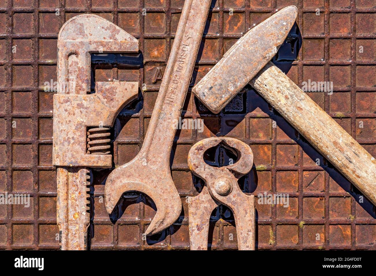 Vecchio utensile con inglese, chiave, pinza di fissaggio, martello su piastra in ferro arrugginito umido, Germania Foto Stock