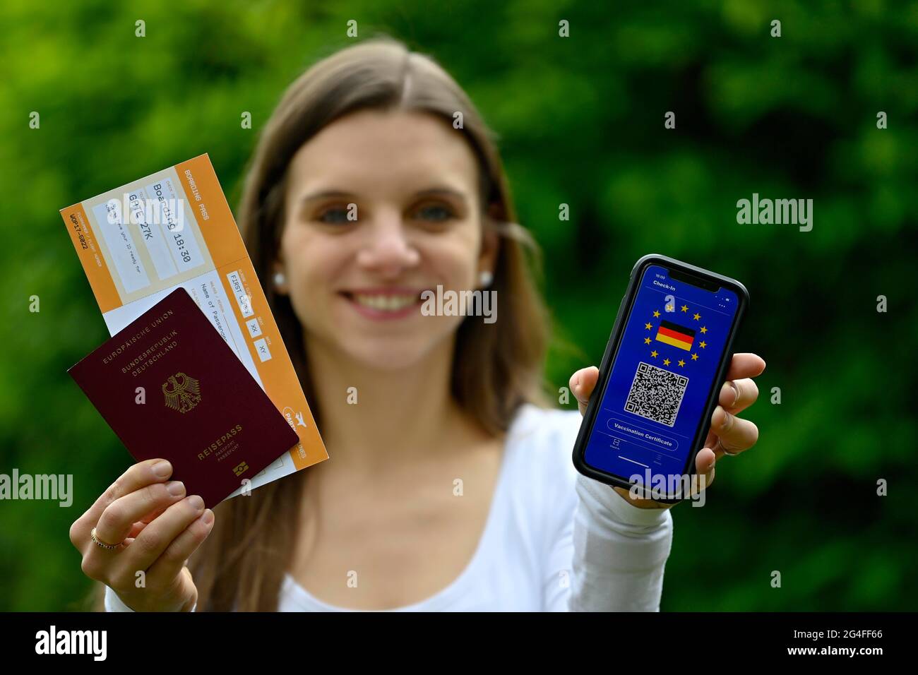 Simbolo foto vaccinazioni privilegio, giovane donna con smartphone con passaporto europeo digitale per vaccinazioni per i cittadini tedeschi, con codice QR Foto Stock