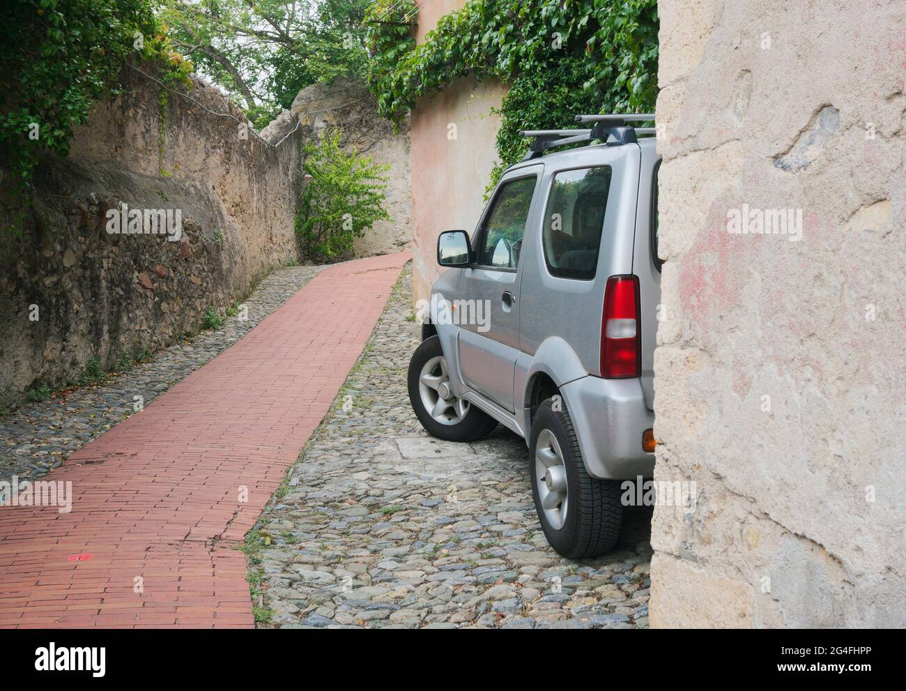Un SUV parcheggiato su un vicolo acciottolato murato in Italia Foto Stock
