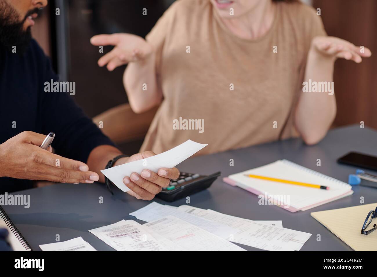 Mani di uomo confuso mostrando ricevuta a moglie che ha fatto grande acquisto e speso un sacco di soldi senza parlare con lui prima Foto Stock
