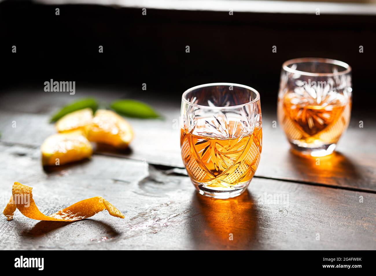 Due bicchieri con liquore alla mandarino su un vecchio sfondo di legno Foto Stock