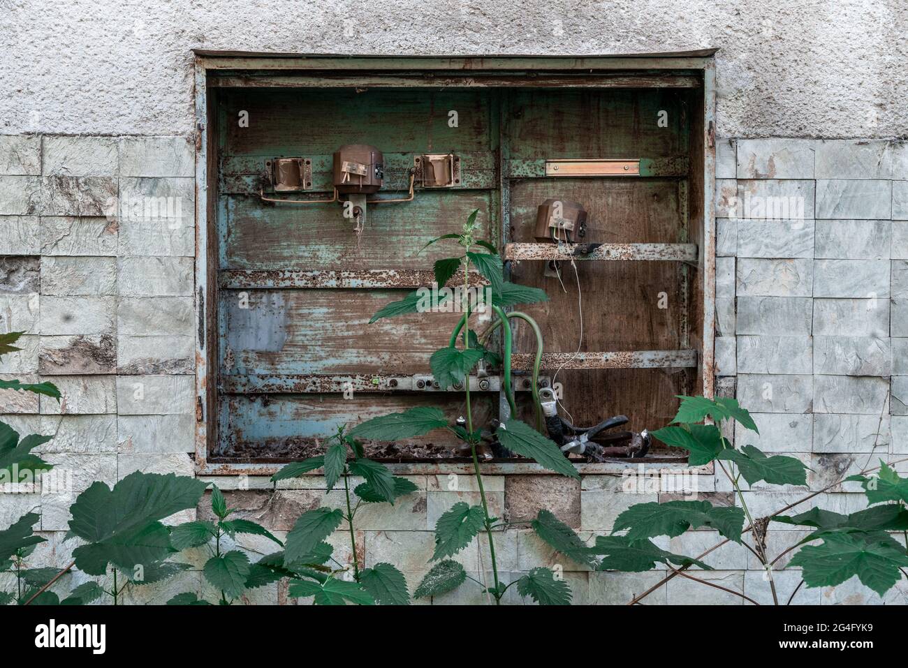 Particolare di un vecchio quadro elettrico con la maggior parte delle parti mancanti, costruito in una facciata di un antico edificio abbandonato che cade a pezzi Foto Stock