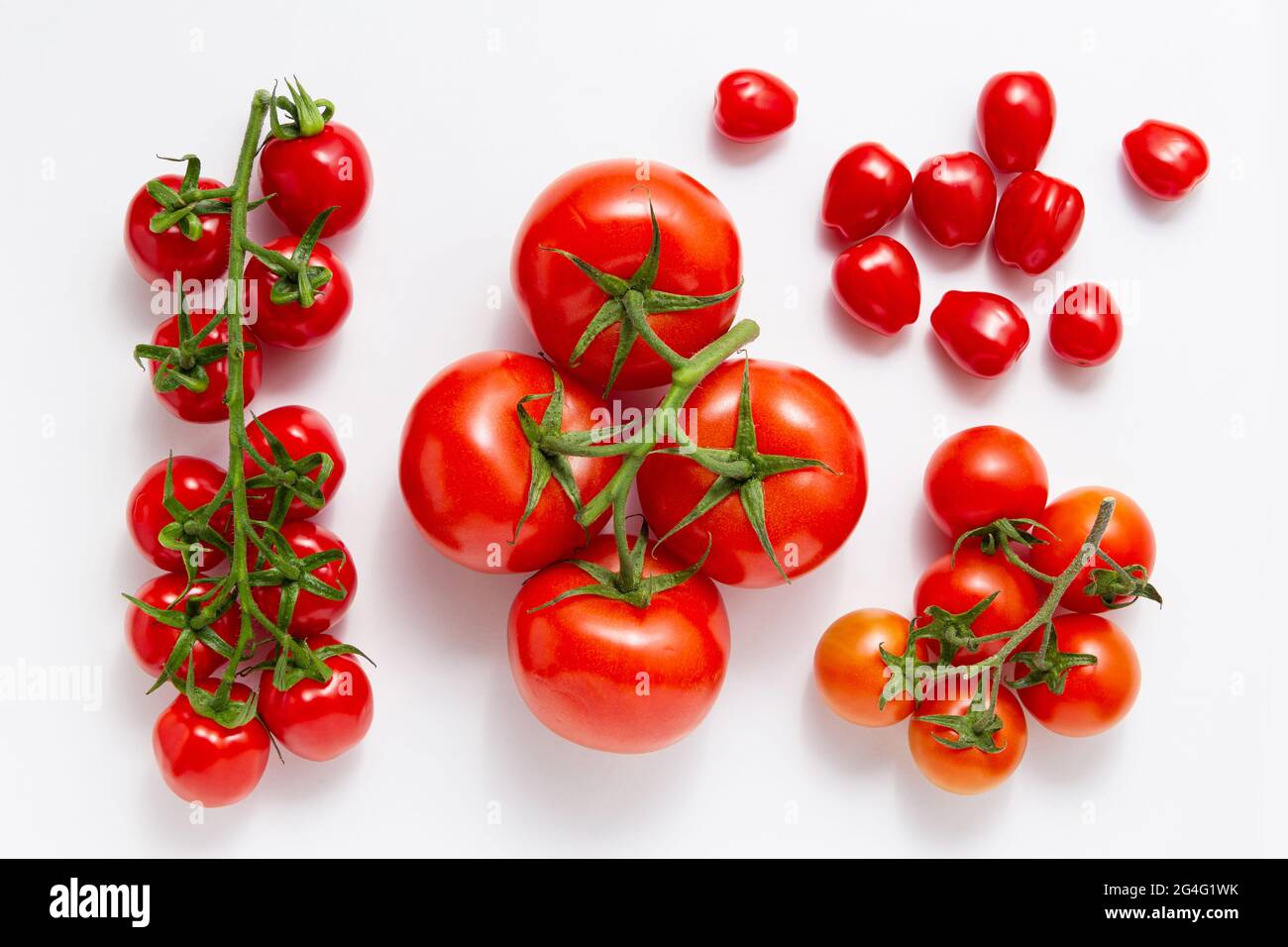 Diversi tipi di pomodori su sfondo bianco. Vista dall'alto delle verdure fresche. Foto Stock