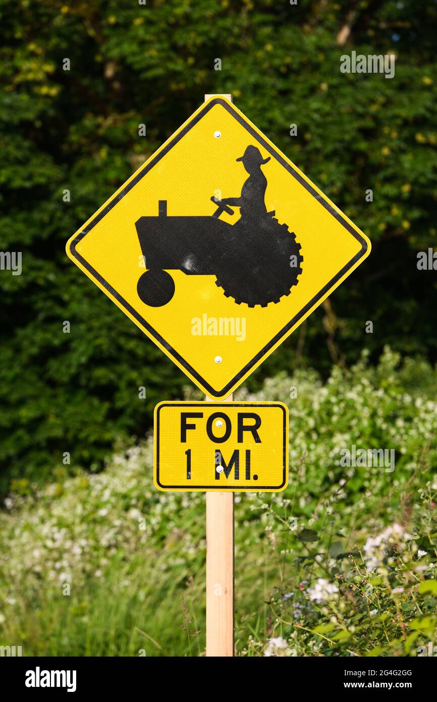 Garofano, WA, USA - 18 giugno 2021; cartello di avvertimento di un'azienda agricola con un coltivatore su un trattore in nero su un segno di diamante giallo Foto Stock