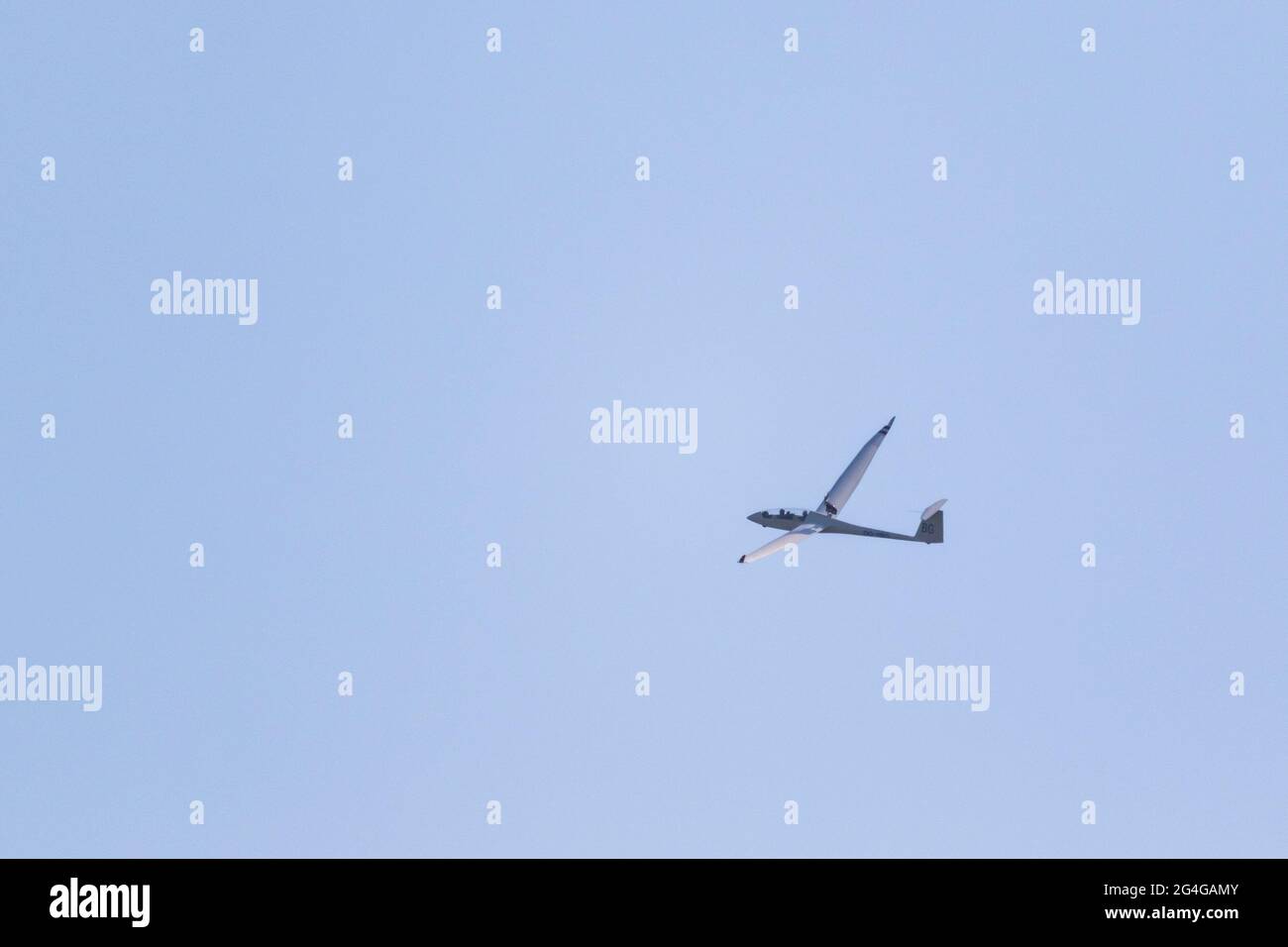 Un ritratto di un aliante che vola in lontananza in un cielo azzurro. L' aereo sta sorvolando attraverso l'aria senza un motore a getto o un'elica,  da noi Foto stock - Alamy