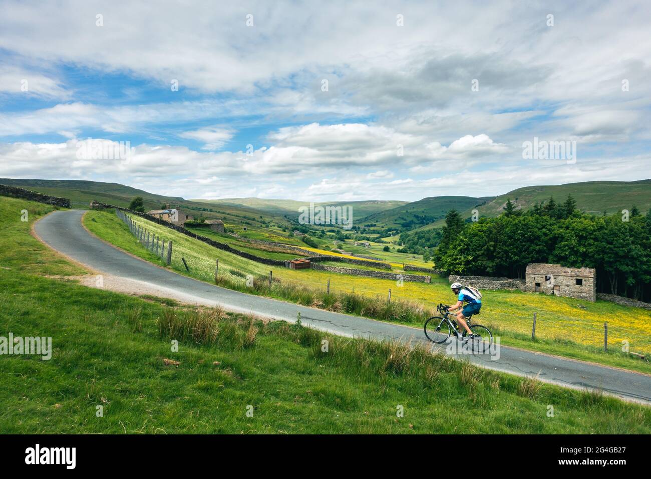 Ciclisti in bicicletta la ripida strada recintata di Satron Moor fuori da Swaledale, Yorkshire Dales National Park, paesaggio britannico Foto Stock
