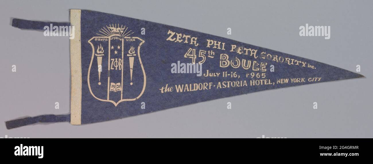 La Zeta Phi Beta Soriority è stata fondata nel gennaio 1920 presso la Howard University, storicamente università di ricerca nera, a Washington, D.C. questo pennant in feltro a forma triangolare è un blu reale sbiadito sul fronte. Ha una striscia bianca lungo un bordo diritto corto e una scritta bianca che recita "ZETA PHI BETA SORIORITY Inc. / 45th Boule/ 11-16 luglio 1965/ The Waldorf-Astoria Hotel, New York City." A sinistra delle lettere si trova la cresta di soriorità. Questa raffigura una forma di scudo con quattordici raggi emanati dalla parte superiore. Lo scudo stesso è diviso in tre campi. Le due f più esterne Foto Stock