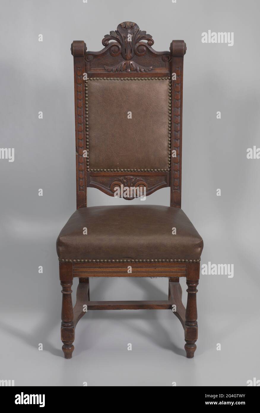 Una sedia in legno a pulpito con finitura scura. La sedia è dotata di  quattro gambe con le gambe posteriori che si estendono per l'intera altezza  dello schienale. Le gambe anteriori sono