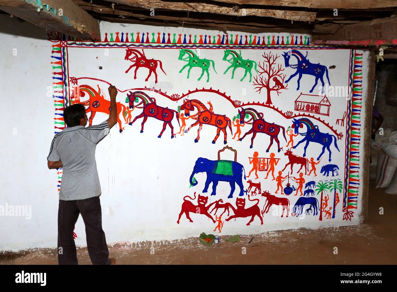 RATHAWA TRIBÙ artisti tribali disegnando Pithora pittura su un muro di fango all'interno di una casa. I dipinti di Pithora sono altamente arricchiti cultura d'arte popolare del Gujarat Foto Stock