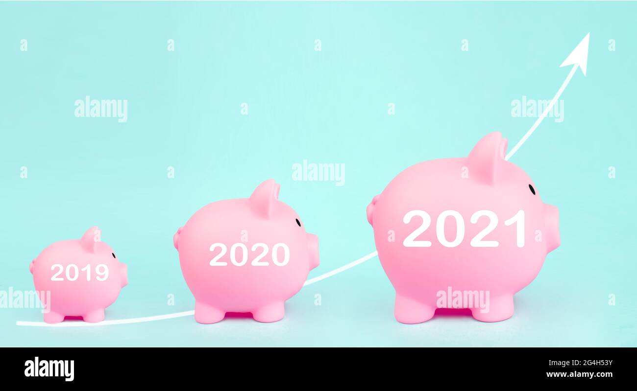 Banchi di piggy rosa con ologramma digitale freccia bianca e segno di 2021 anni su sfondo blu. Crescita degli investimenti, risparmio finanziario ed economia bancaria. Foto Stock