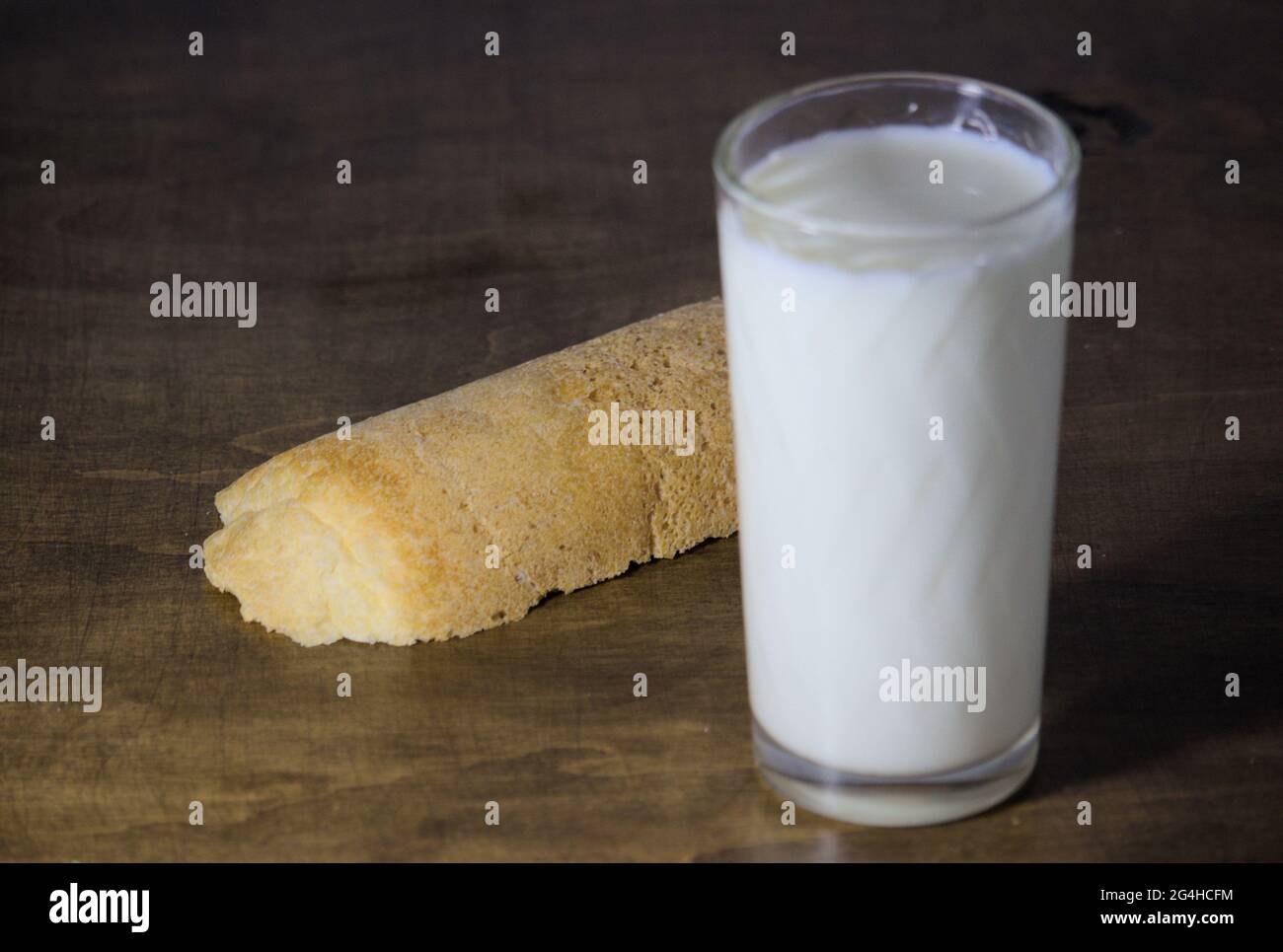 Bicchiere di latte e pezzo di pane (non focalizzato) sullo sfondo Foto Stock