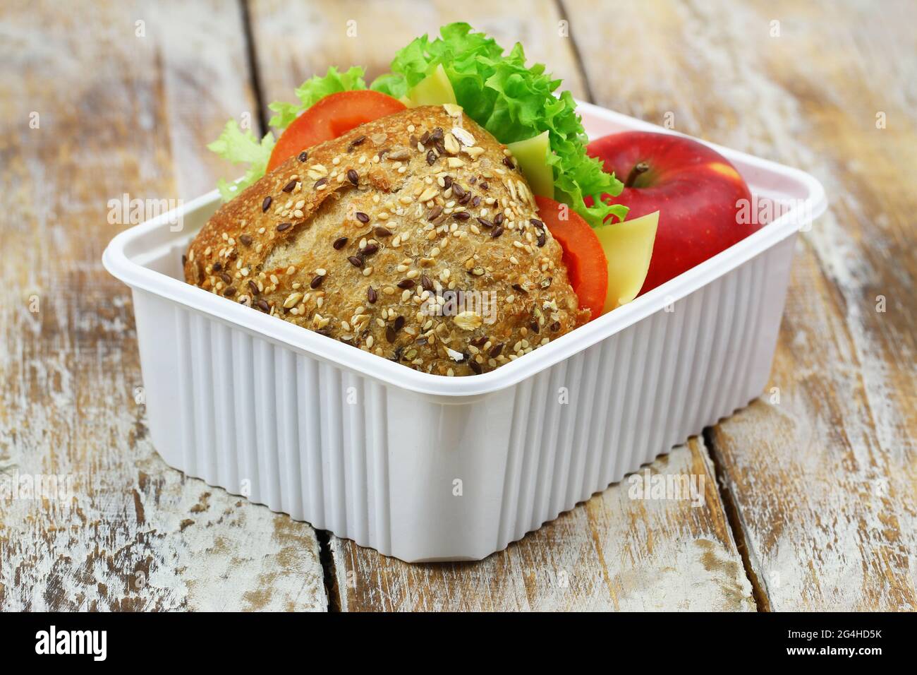 Pranzo sano a scuola con panino di formaggio a grani interi con pomodori, lattuga e mela rossa Foto Stock