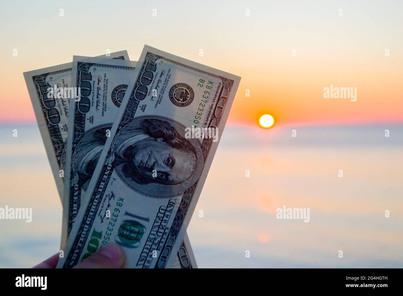 Bollette di trecento dollari sullo sfondo della superficie del mare all'alba del tramonto Foto Stock