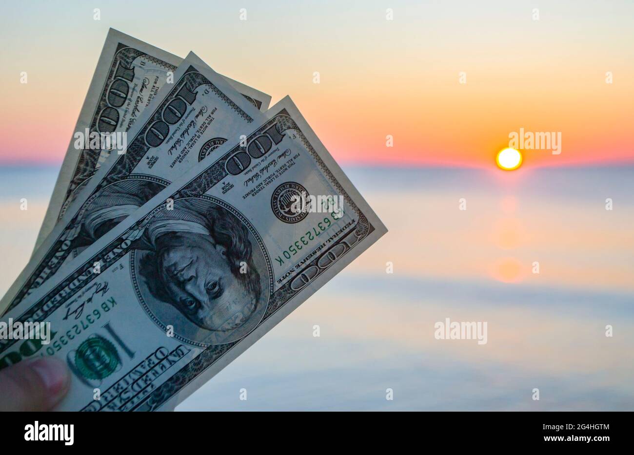 Bollette di trecento dollari sullo sfondo della superficie del mare all'alba del tramonto Foto Stock