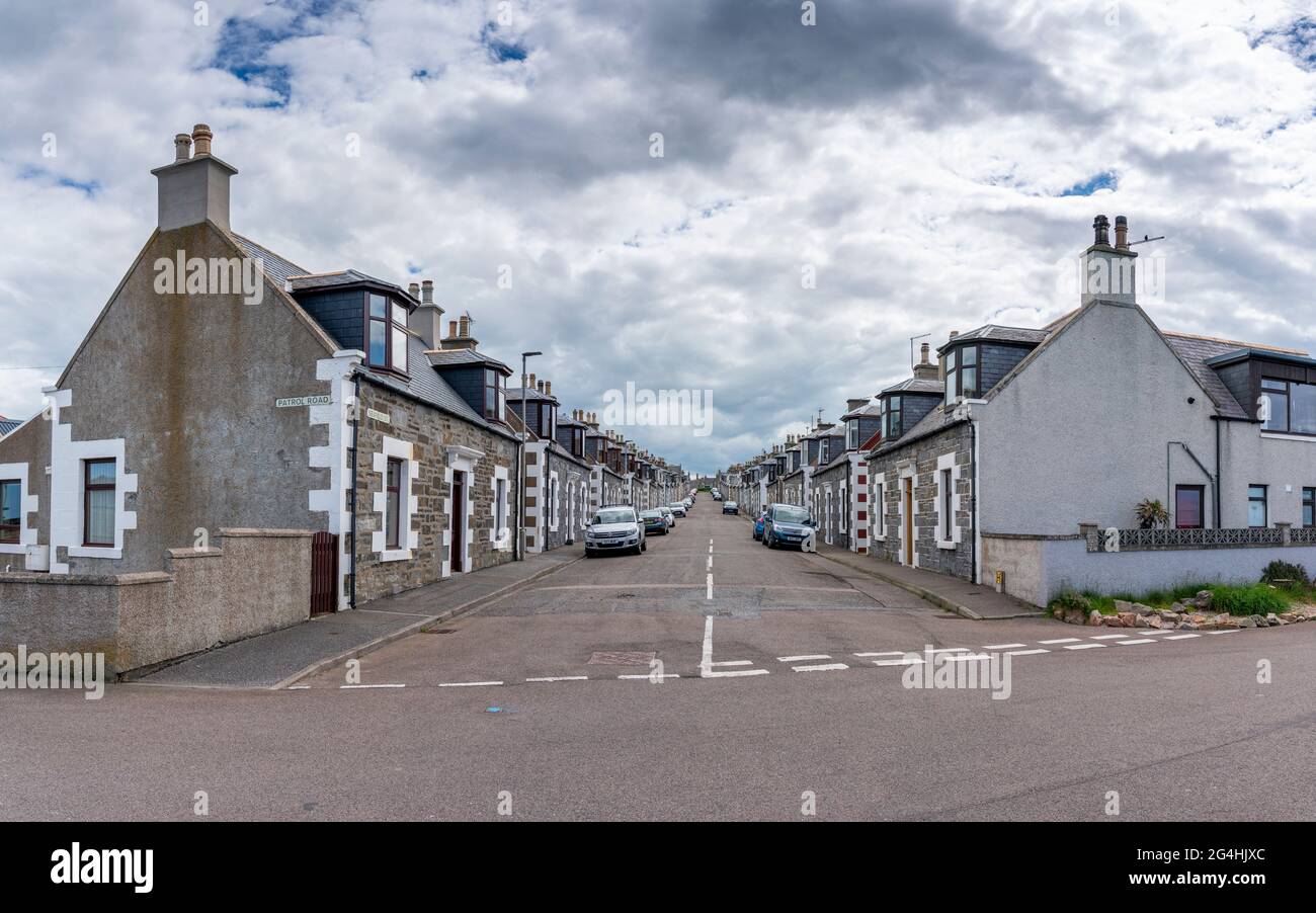 Vista lungo la strada fiancheggiata da ex cottage dei pescatori a Portknockie, Moray, Scozia, Regno Unito Foto Stock