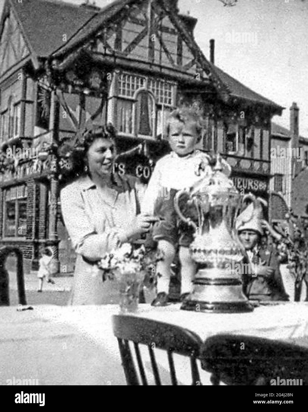 I festosi tifosi di Portsmouth Florrie Farr e il nipote David Copus, due, posano con la fa Cup durante una festa di strada di VE fuori Fratton Park nel 1945, quando Pompey tenne la coppa per sette anni dopo la loro vittoria di Wembley del 4-1 sui lupi a causa della seconda guerra mondiale. La coppa, che Pompey può recuperare dopo un'assenza di 69 anni battendo Cardiff oggi (Sab), è stato permesso ai membri del pubblico senza alcuna polizia o sicurezza a portata di mano per proteggerla. PIC MIKE WALKER IMMAGINI GIOCA SU POMPEY (1) inviato da Michael Harvey di Cosham vediamo il piccolo ragazzo di 2 anni chiamato David Copus con la sua zia Florrie (Farr) a un st Foto Stock