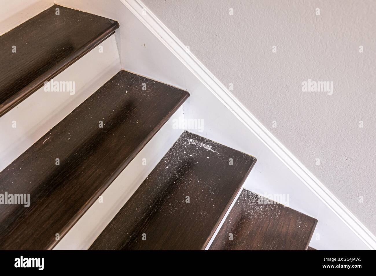 scale in legno verniciato bianco e colorato scuro in una nuova casa di costruzione con polvere di roccia di pietra da buco nella parete sopra Foto Stock