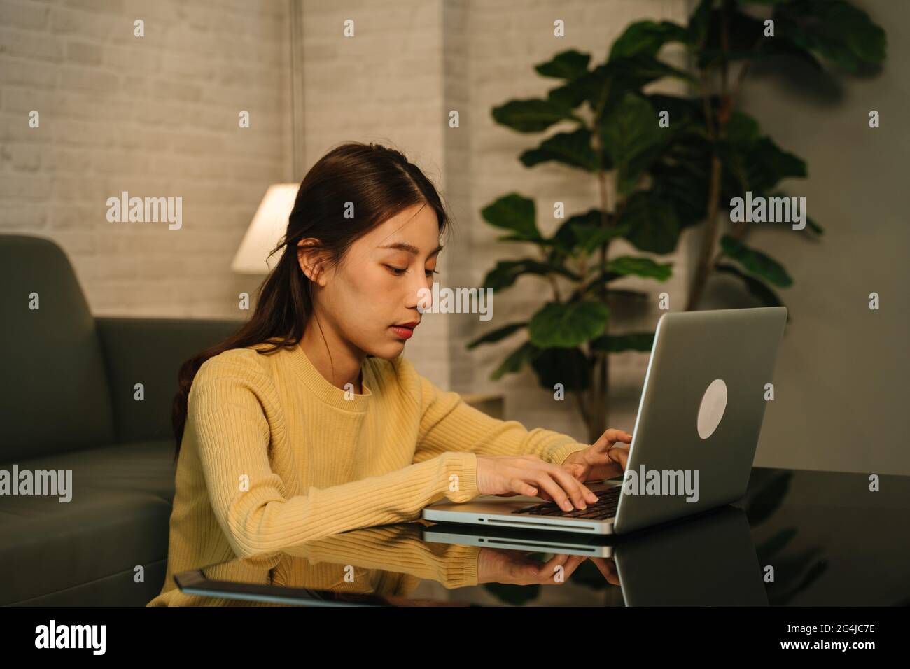 Lavoraholic e stanco giovane donna d'affari asiatica che lavora straordinario sul laptop fino a tarda notte completando il progetto del cliente a casa Foto Stock