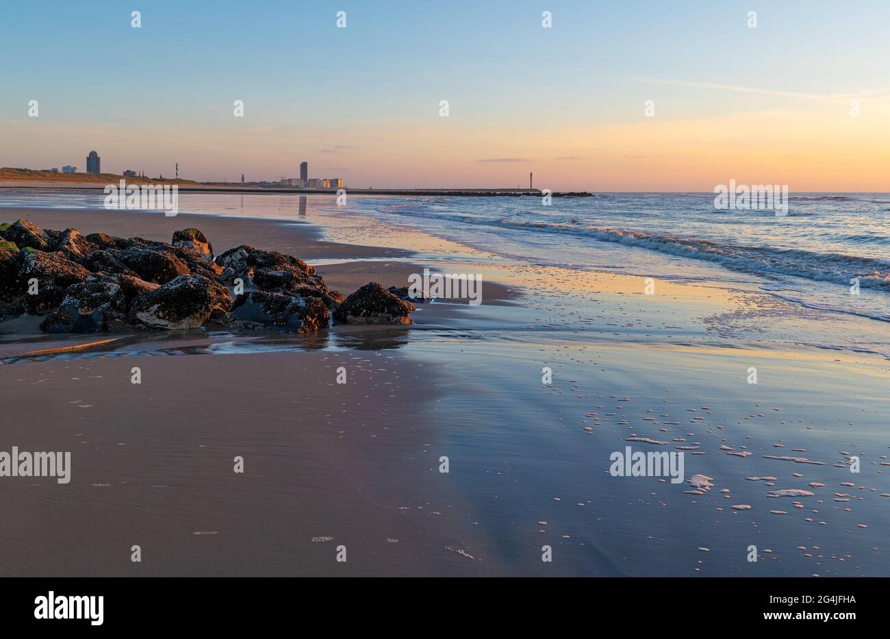 Spiaggia di Ostenda (Ostenda) con skyline e molo al tramonto con frangiflutti lungo il Mare del Nord, le Fiandre, Belgio. Foto Stock