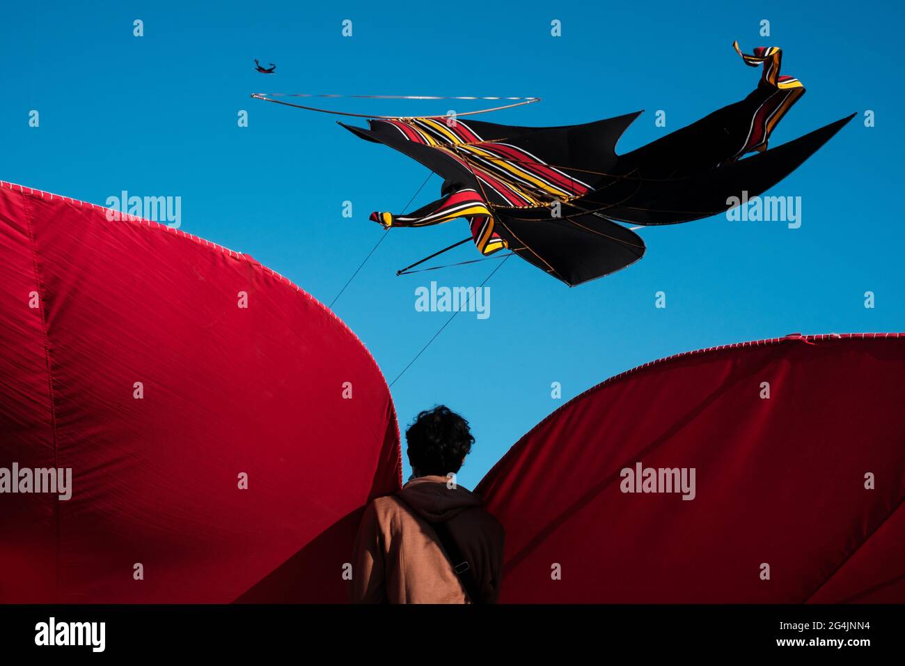 Il ragazzo balinese tiene UN kite gigante contro UN cielo blu chiaro Foto Stock