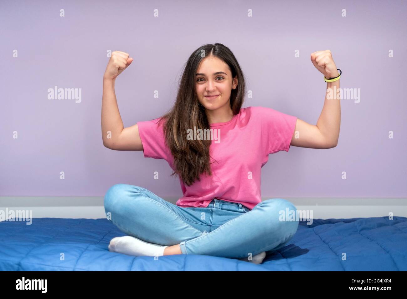 Ritratto a lunghezza intera di una ragazza adolescente sana e fresca che sorride mentre si posa con le braccia flette mostrando forza muscolare e immunità Foto Stock