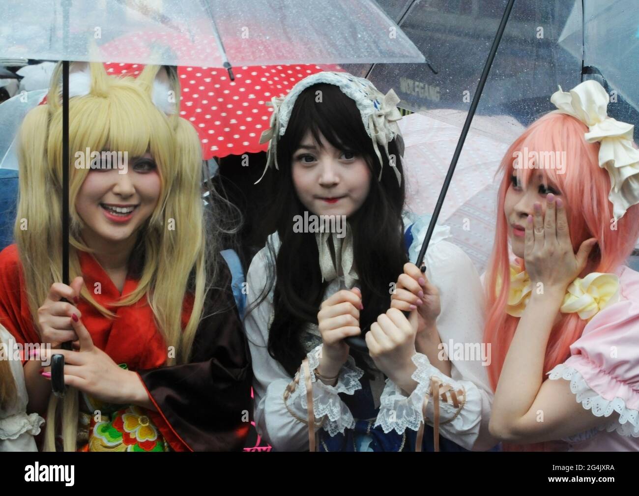3 ragazze giapponesi con ombrelli vestiti in stile manga. Tokyo, Giappone. Foto Stock