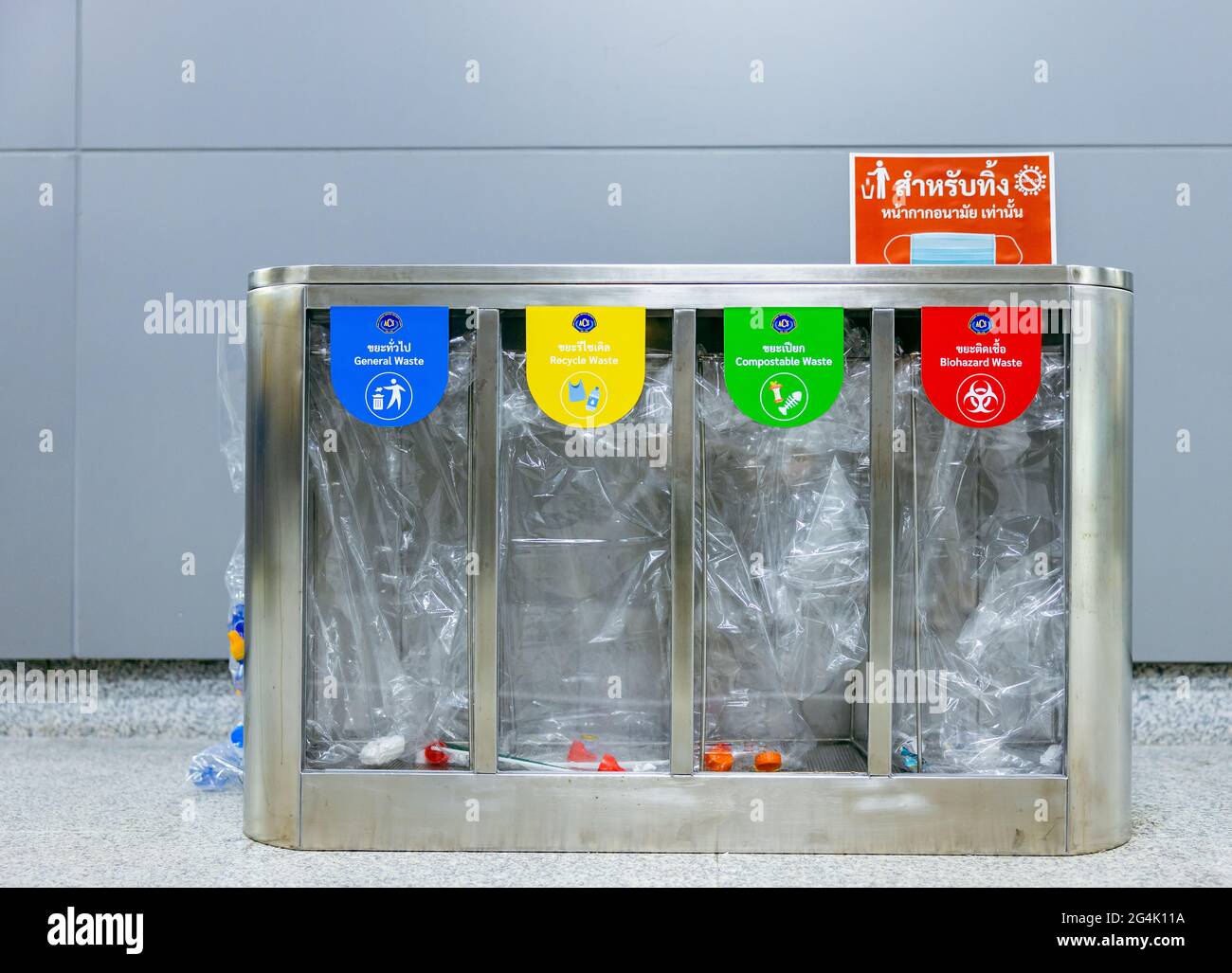 BANGKOK, THAILANDIA - 21 giu 2021: Riciclaggio di selezione giallo, verde, blu e rosso riciclare contenitori trasparenti con simbolo di riciclaggio sullo sfondo della parete Foto Stock