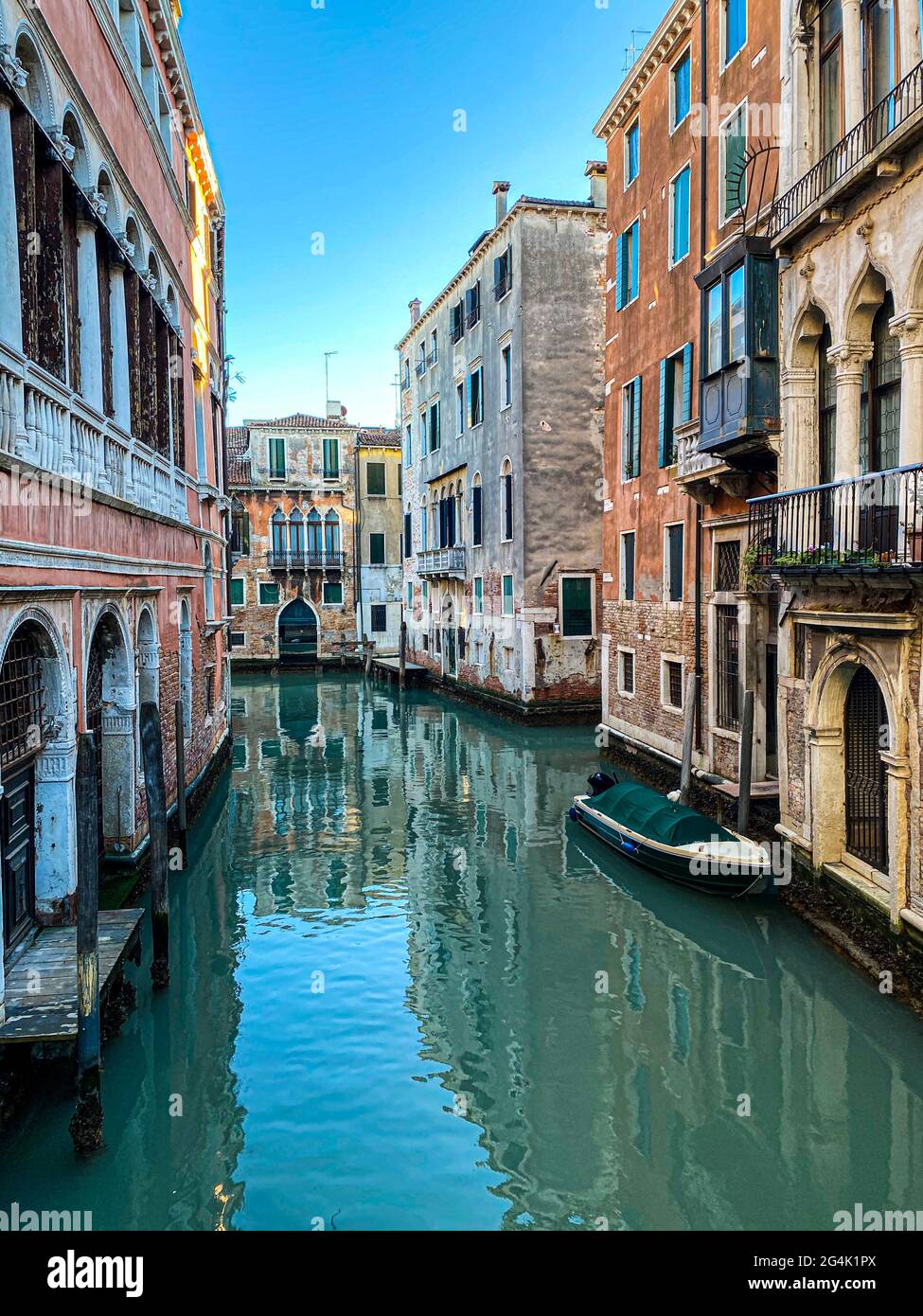 Piccola barca su una strada canale a Venezia con belle case colorate, Italia. Cielo blu Foto Stock