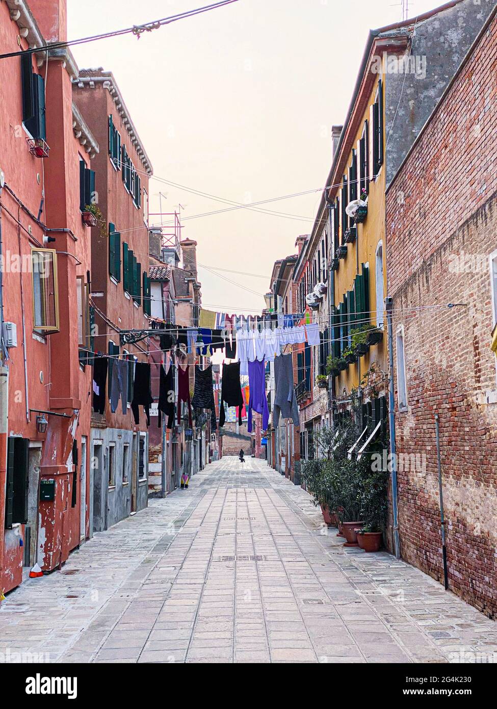 Colorata strada senza uscita a Venezia con un sacco di lavanderia appendere ad asciugare in linee tese tra le case Foto Stock