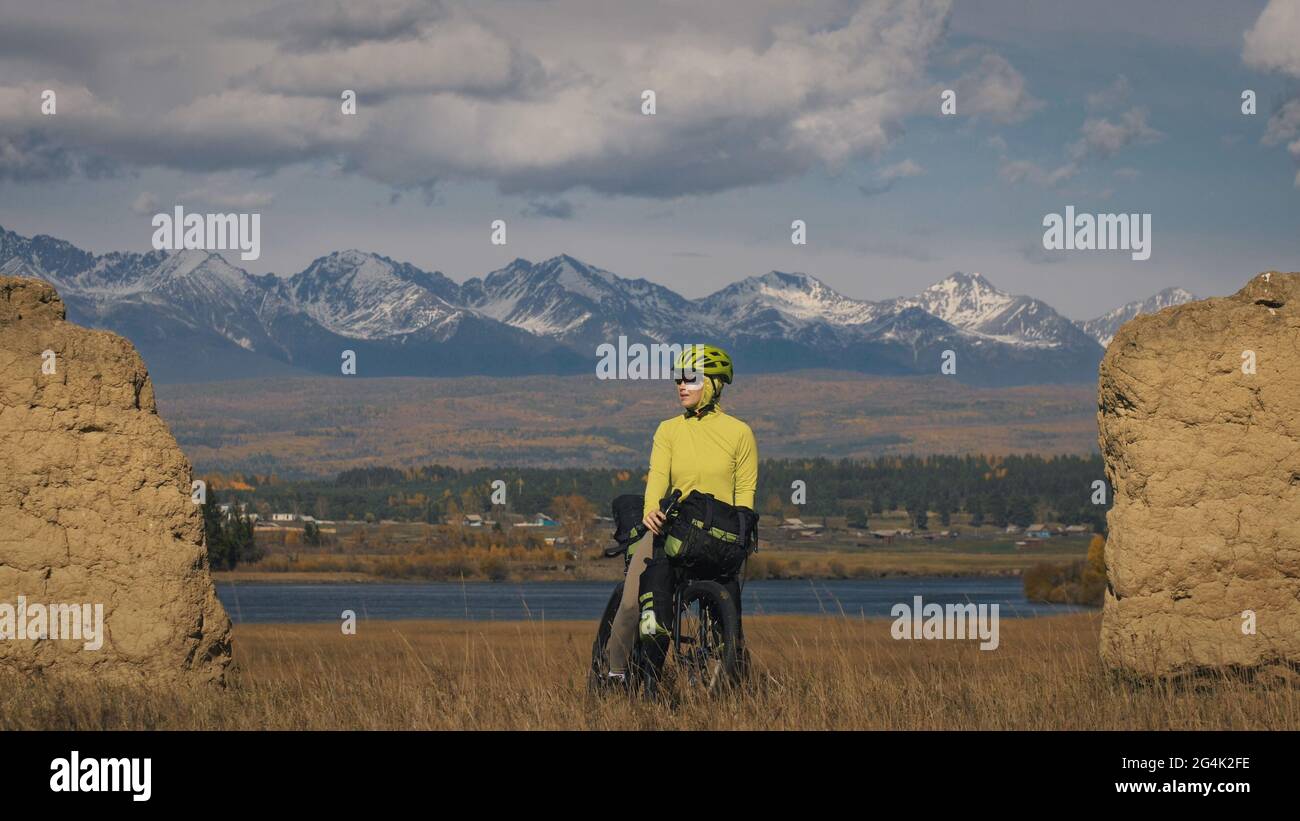 La donna viaggia in bicicletta su terreni misti con bikepacking. Il viaggio del viaggiatore con le borse della bicicletta. Sport turismo bikepacking. Foto Stock