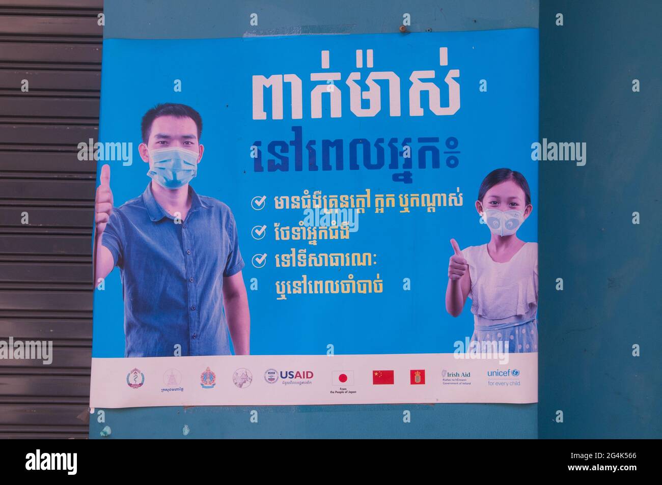 Durante un focolaio di COVID - 19, USAID mette in su i manifesti in scritto Khmer che avvertiscono la gente di indossare le maschere facciali protettive durante la pandemia del coronavirus. Phnom Penh, Cambogia. 9 Marzo 2021. © Kraig Lieb Foto Stock