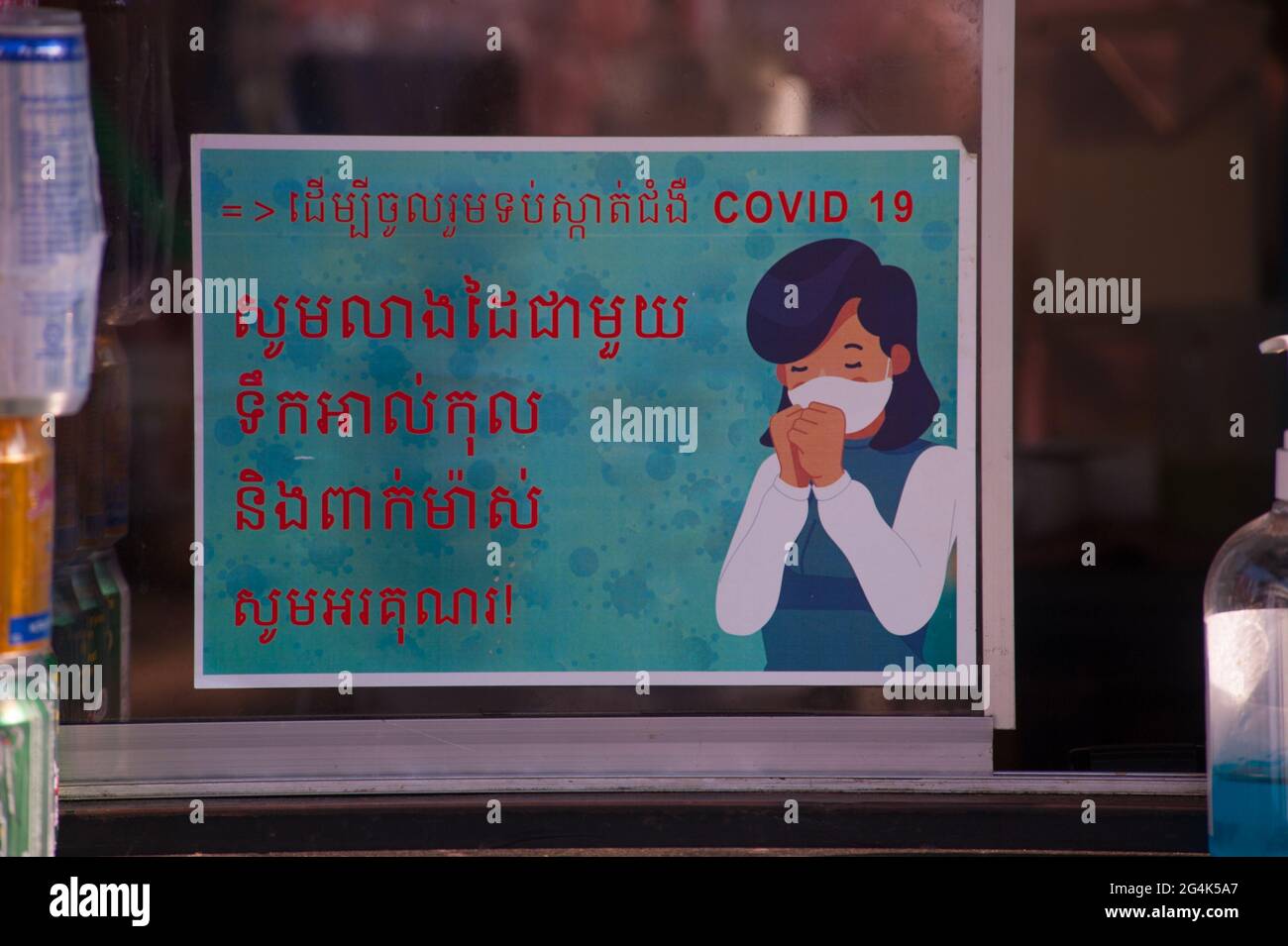 Durante uno scoppio di COVID - 19, un commercio mette in su un segno bilingue in scritto Khmer / scrittura inglese che avverte la gente di indossare le maschere di faccia al mercato di Kandal durante la pandemia del coronavirus. Phnom Penh, Cambogia. 9 Marzo 2021. © Kraig Lieb Foto Stock
