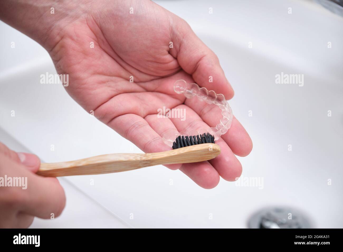 Pulizia degli allineatori dei denti. Lavare e rimuovere i residui organici con uno spazzolino da denti di bambù da tute ortodontiche invisibili. Foto Stock