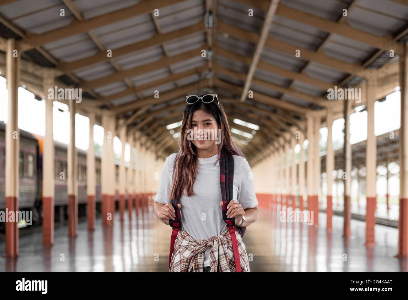 ritratto di una giovane viaggiatore con zaino piccolo sul montante ferroviario. Donna asiatica zaino in spalla viaggio da solo Foto Stock