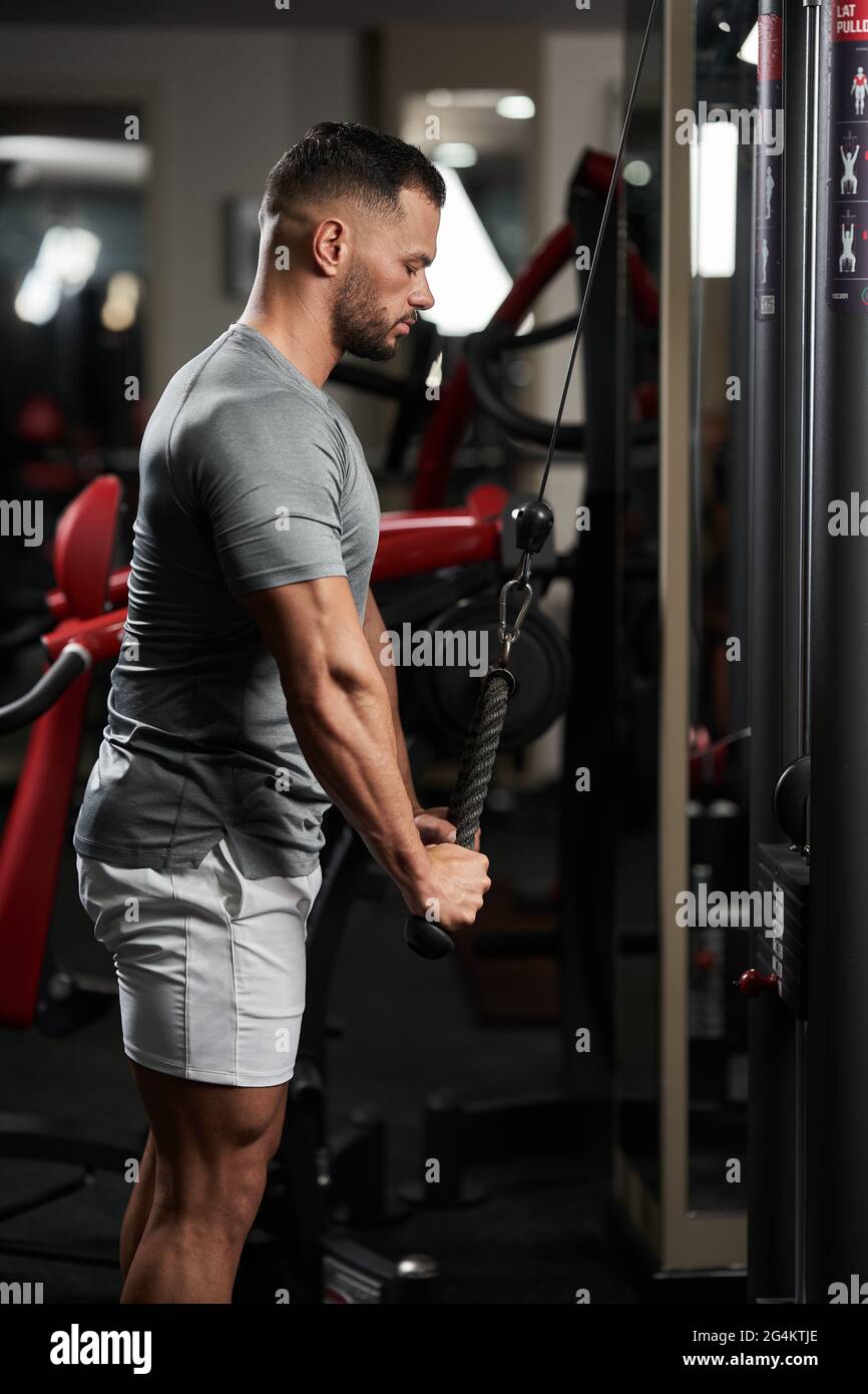 Fitness man facendo allenamento triceps alla macchina via cavo Foto Stock