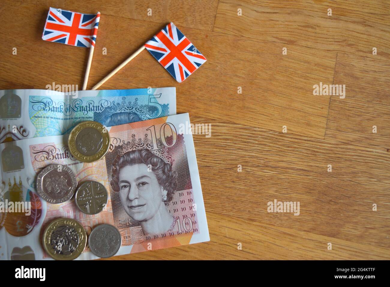 Monete e banconote britanniche con bandiere piccole. Foto Stock