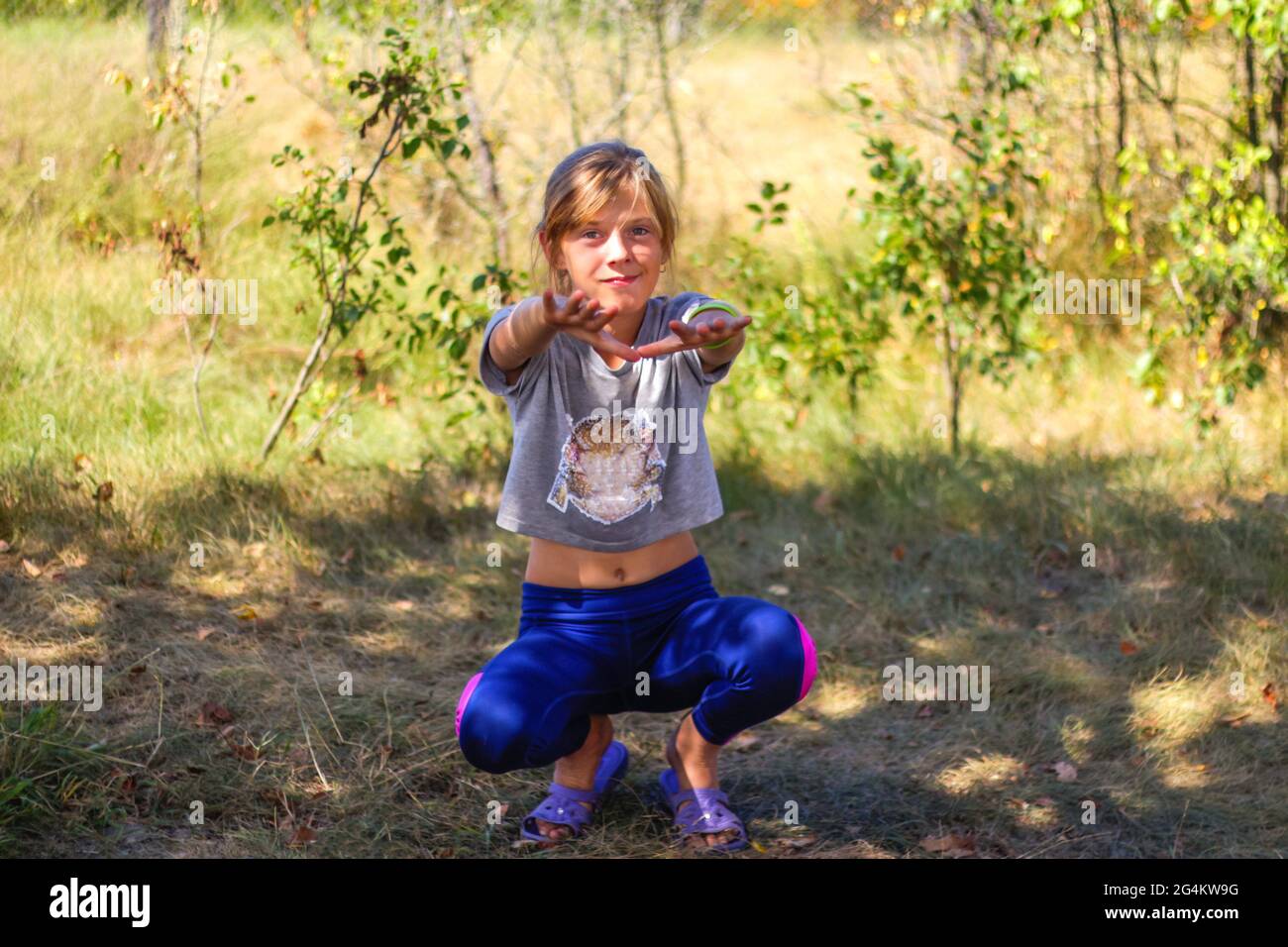 Defocus caucasico presteen ragazza facendo esercizio fisico in parco, foresta, all'aperto, all'esterno. Uno stile di vita sano e benessere. Squadre con braccia estese. Natur Foto Stock