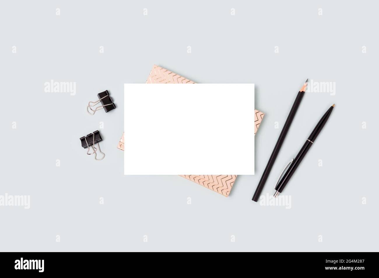 Cartoncino di carta mockup e cancelleria su sfondo blu. Area di lavoro minimalistica. Foto Stock