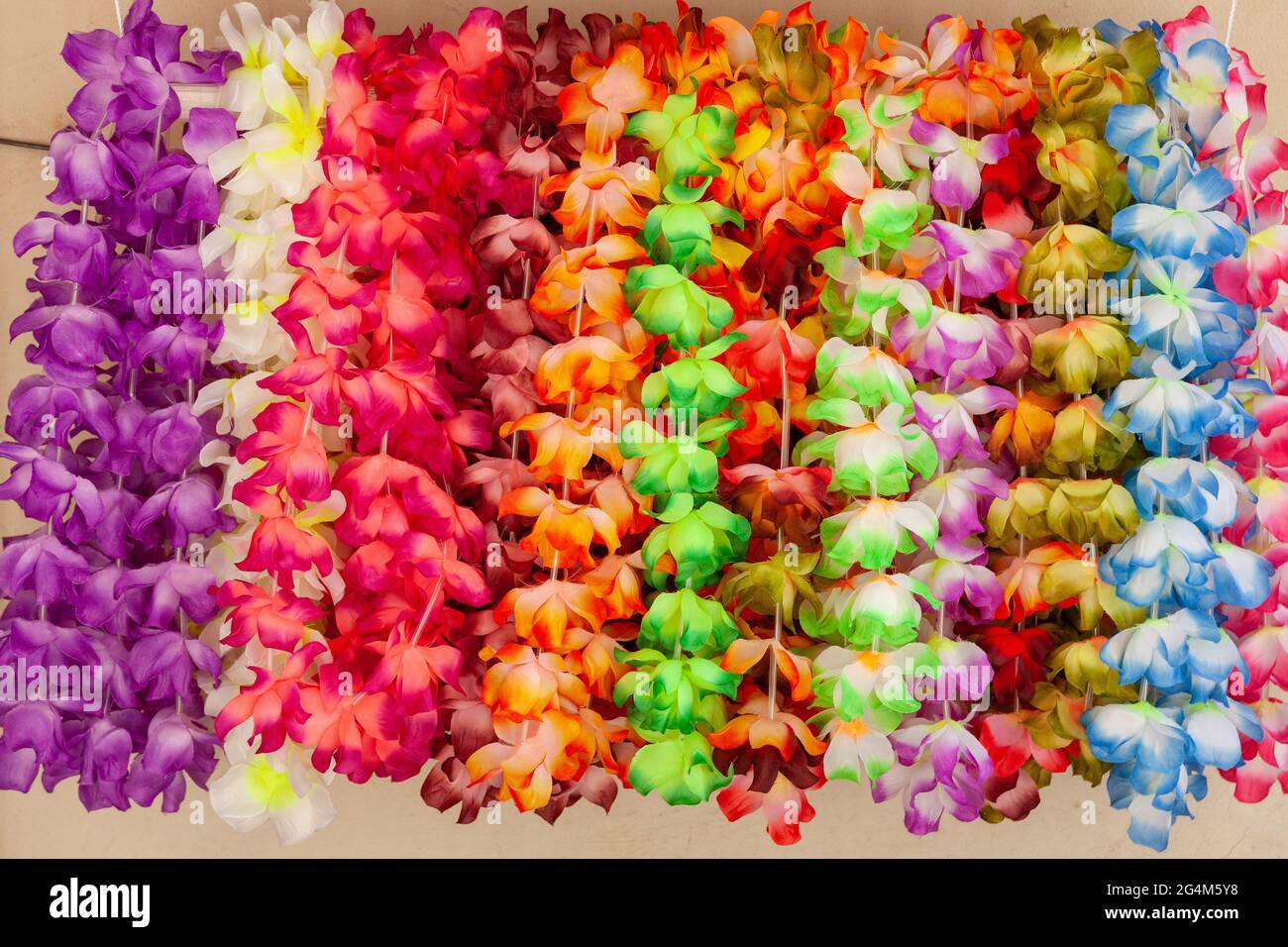 Collane di fiori multicolore su sfondo di una parete gialla. Bonifacio, Corsica. Francia Foto Stock