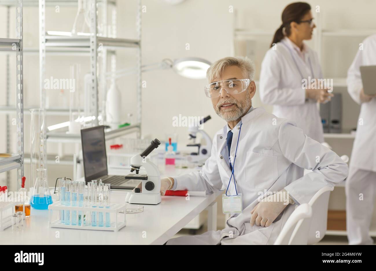 Professore anziano di scienziato seduto sul posto di lavoro in un laboratorio moderno Foto Stock