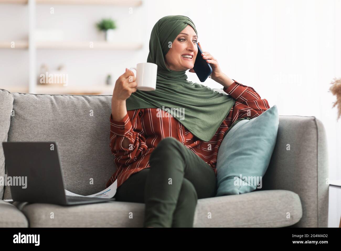 Signora Medio-Orientale matura in Hijab che parla su Cellphone a casa Foto Stock