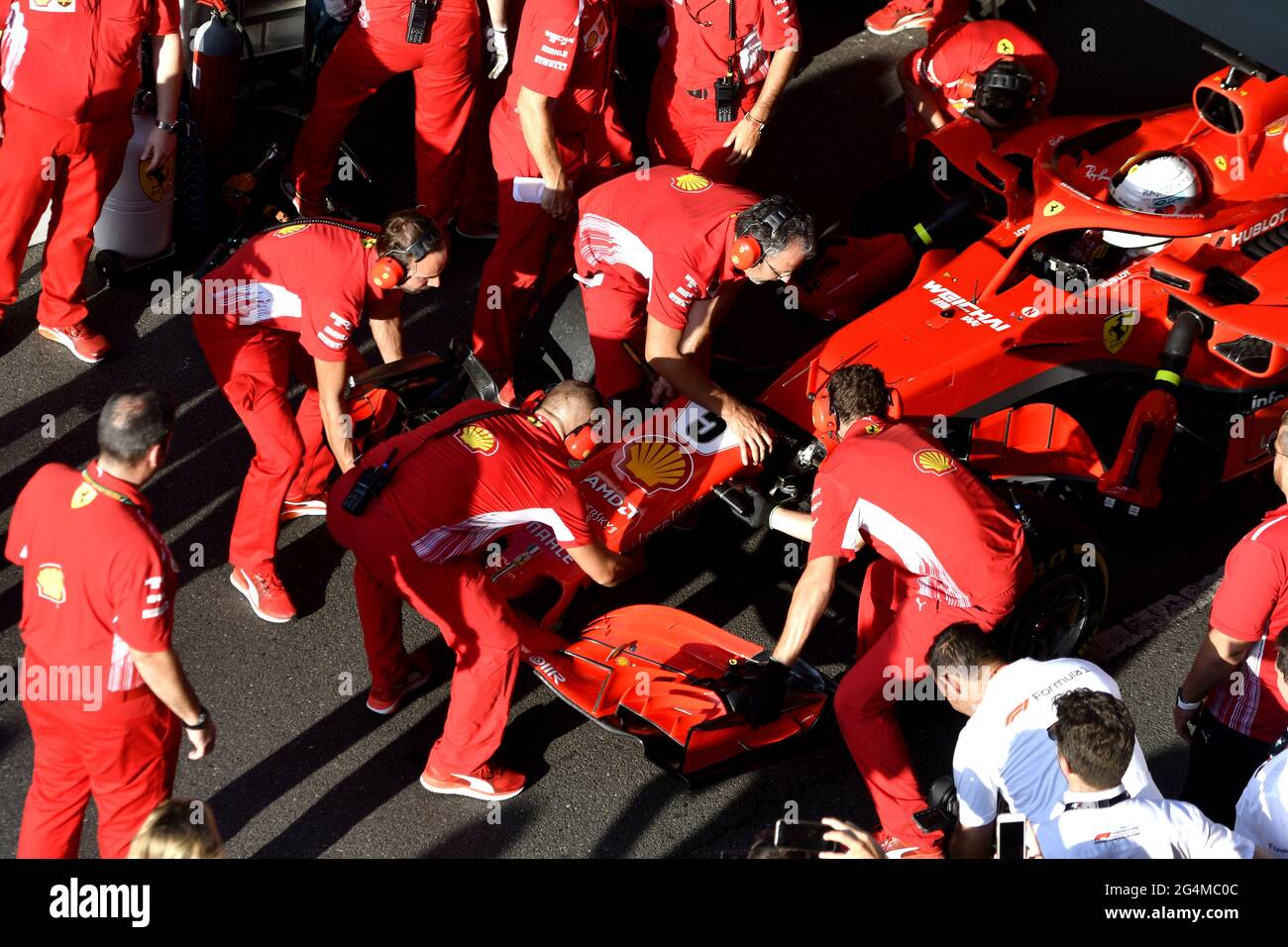 L'equipaggio dei box Ferrari lavora intorno alla Ferrari Formula uno al box Ferrari, durante una mostra a Milano. Foto Stock
