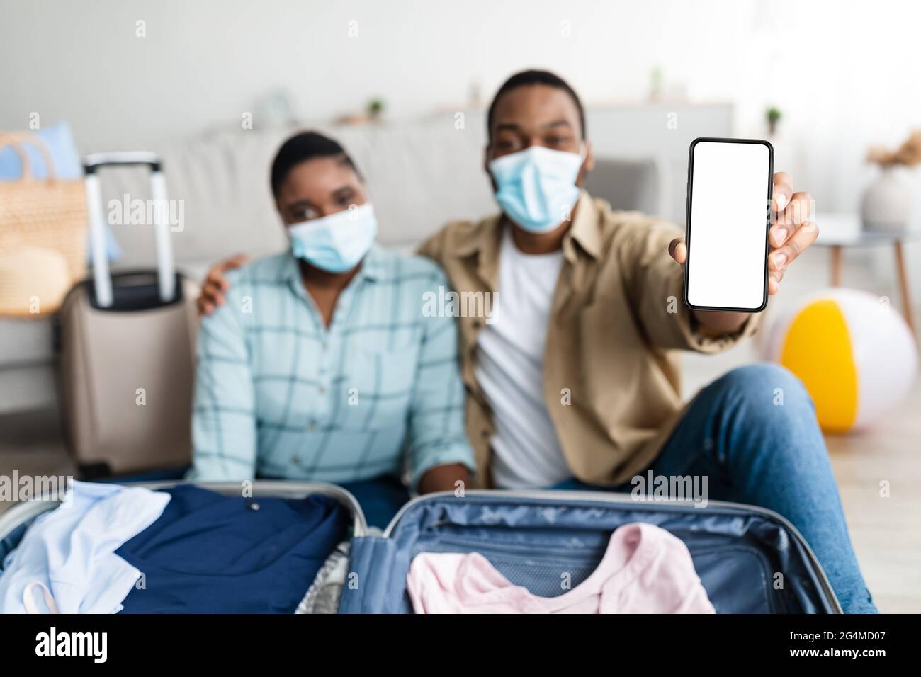 Coppia Africana americana che mostra schermo del telefono interno, che indossa maschere facciali Foto Stock